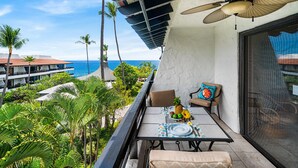 A balcony with a table, chairs, and a view of the ocean. - 🏖️Kona Oceanview Condo w/ Lanai + A/C | Casa 328 (Kailua Kona)