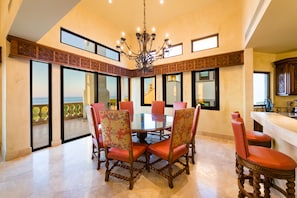 A dining area with a round table, six chairs, and a chandelier.