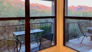 Uma varanda com mesa e cadeiras, com vista para uma paisagem montanhosa.