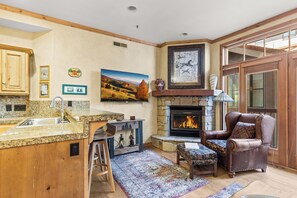A kitchen with granite countertops, a fireplace, and a stone fireplace surround. - Main Street Condo|Steps to Lift |Amazing Rooftop I Managed by Park City Lodging (PARK CITY)