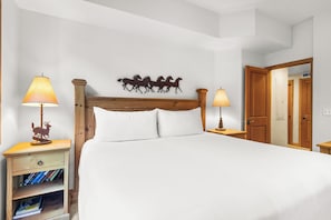 Ein ordentlich bezogenes Bett mit weißen Leinen, einem Holzkopfstück und zwei Nachttischlampen.