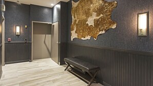 A hallway with a bench, a door, and a large wall decoration.