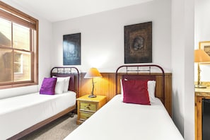A twin room with two beds, a nightstand, a lamp, and artwork on the walls. - Main Street Condo|Steps to Lift |Amazing Rooftop I Managed by Park City Lodging (PARK CITY)