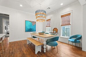 Een eetgedeelte met een houten tafel, blauwe stoelen, een bank en een kroonluchter.