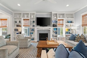A living room with a fireplace, a television, and bookshelves.