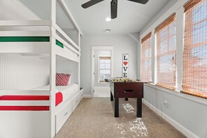 Een kinderkamer met stapelbedden, een tafelvoetbaltafel en een muur met een 'LOVE' bord.