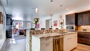 Una cocina moderna con encimeras de granito, electrodomésticos de acero inoxidable y muebles oscuros.
