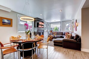 Un interior moderno con comedor, sala de estar y chimenea.