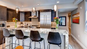 Una cocina moderna con armarios de madera oscura, electrodomésticos de acero inoxidable y una isla de mármol con taburetes de bar.