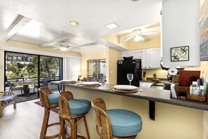 A kitchen with a bar area, a refrigerator, and a sign about no smoking.