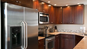 Une cuisine moderne dotée d’appareils électroménagers en acier inoxydable, d’armoires en bois et de plans de travail en granit.