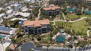 Vista aerea di un resort con diversi edifici, una piscina centrale e vegetazione circostante.