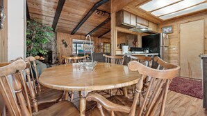 Un intérieur en bois avec une table à manger ronde et des chaises, une cheminée et un coin cuisine.