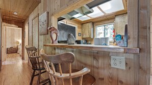Un intérieur en bois comprenant un espace bar, deux tabourets de bar en bois et un comptoir de cuisine.