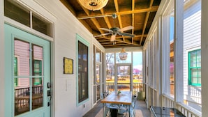 Eine überdachte Veranda mit Tisch und Stühlen, einem Deckenventilator und Blick ins Freie.
