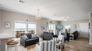 A spacious living room with a large window, a chandelier, and a television.