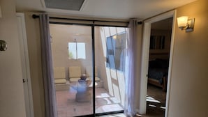 Une pièce dotée d’une porte-fenêtre coulissante donnant sur un espace extérieur aménagé avec des chaises et une table.
