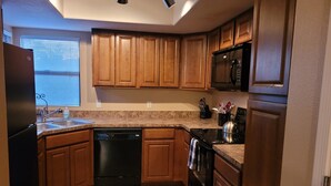 A kitchen with wooden cabinets, a dishwasher, an oven, and a microwave. - Amazing Mountain Views from this 2nd Floor Large 2 Bedroom in Ventana Canyon! (Tucson)