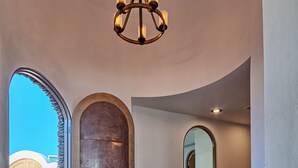 A spacious interior with a curved wooden floor, a large wooden door, and a chandelier.