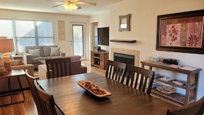 A dining area with a wooden table, chairs, and a fireplace. - Tucson flair in this 2nd floor-serene patio -close to main pool- exercise rm (Tucson)