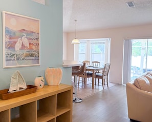 A dining area with a table and chairs, a pendant light, and a window with a view of greenery. - Vacation Home with Private Pool Near Disney (Davenport)