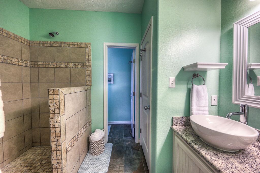 Een badkamer met een douche, een wastafel en een spiegel.