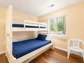 Ein Schlafzimmer mit Etagenbett, Fenster und weißem Stuhl.
