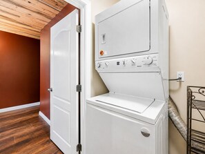 A laundry room with a white washer and dryer, a wooden door, and a metal rack.