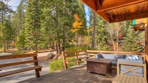 A wooden deck with outdoor seating, surrounded by a forested area. - Cozy Wood Cabin By Tahoe Getaways - 3 BR w Hot Tub, Fireplace + Backs to Forest (Carnelian Bay)