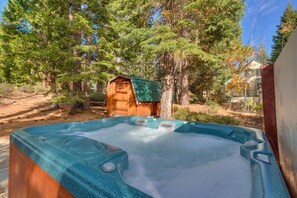 Un bain à remous situé dans un espace boisé, avec un abri en bois en arrière-plan.