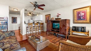 Ein Wohnzimmer mit Fernseher, Korbmöbeln und Deckenventilator.