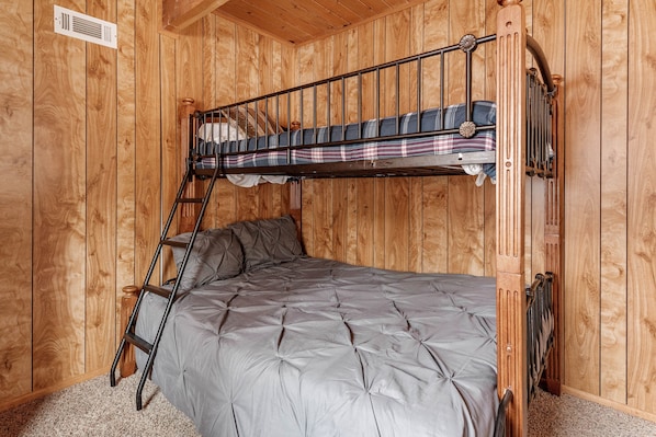 A bunk bed with a ladder, a wooden wall, and a radiator.