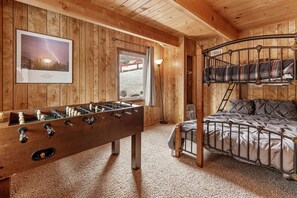 Een gezellige kamer met houten wanden, een futonbed, een tafelvoetbaltafel en een lijst met een foto van bliksem.