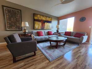 A living room with a sofa, armchair, coffee table, and two lamps.