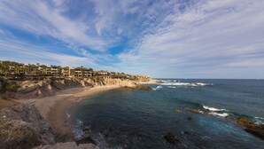 A coastal hotel with a beachfront view, rocky shoreline, and ocean waves. - Resort Living in Ocean View Penthouse at Esperanza (Cabo San Lucas)