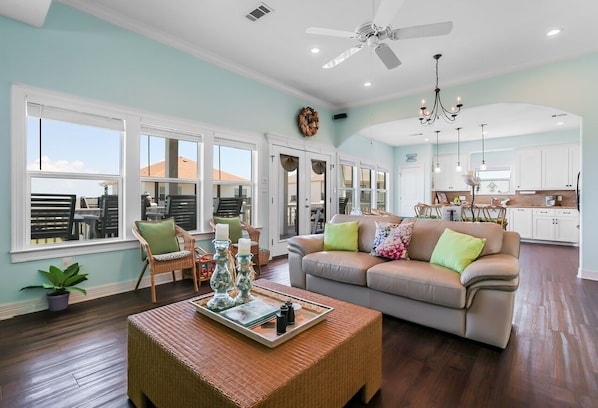 A spacious living room with a beige sofa, a wicker coffee table, and a dining area with chairs.