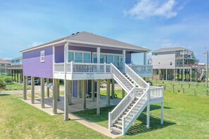 Stilted house with a spacious balcony and staircase leading to an upper level.
