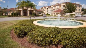 A residential building with a fountain in the center, surrounded by well-maintained bushes. - Elegant Condo w/Pool View Balcony Resort Pool & Gym. Near Disney/Shops (Davenport)