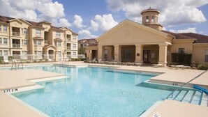 A swimming pool with a 3 FT 3 IN depth, surrounded by a building with a tower and multiple balconies. - Elegant Condo w/Pool View Balcony Resort Pool & Gym. Near Disney/Shops (Davenport)