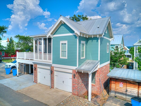 A two-story house with a garage, a covered porch, and a brick foundation. - Carlton Landing! Cozy Garage Apartment close to all amenities! (Carlton Landing)