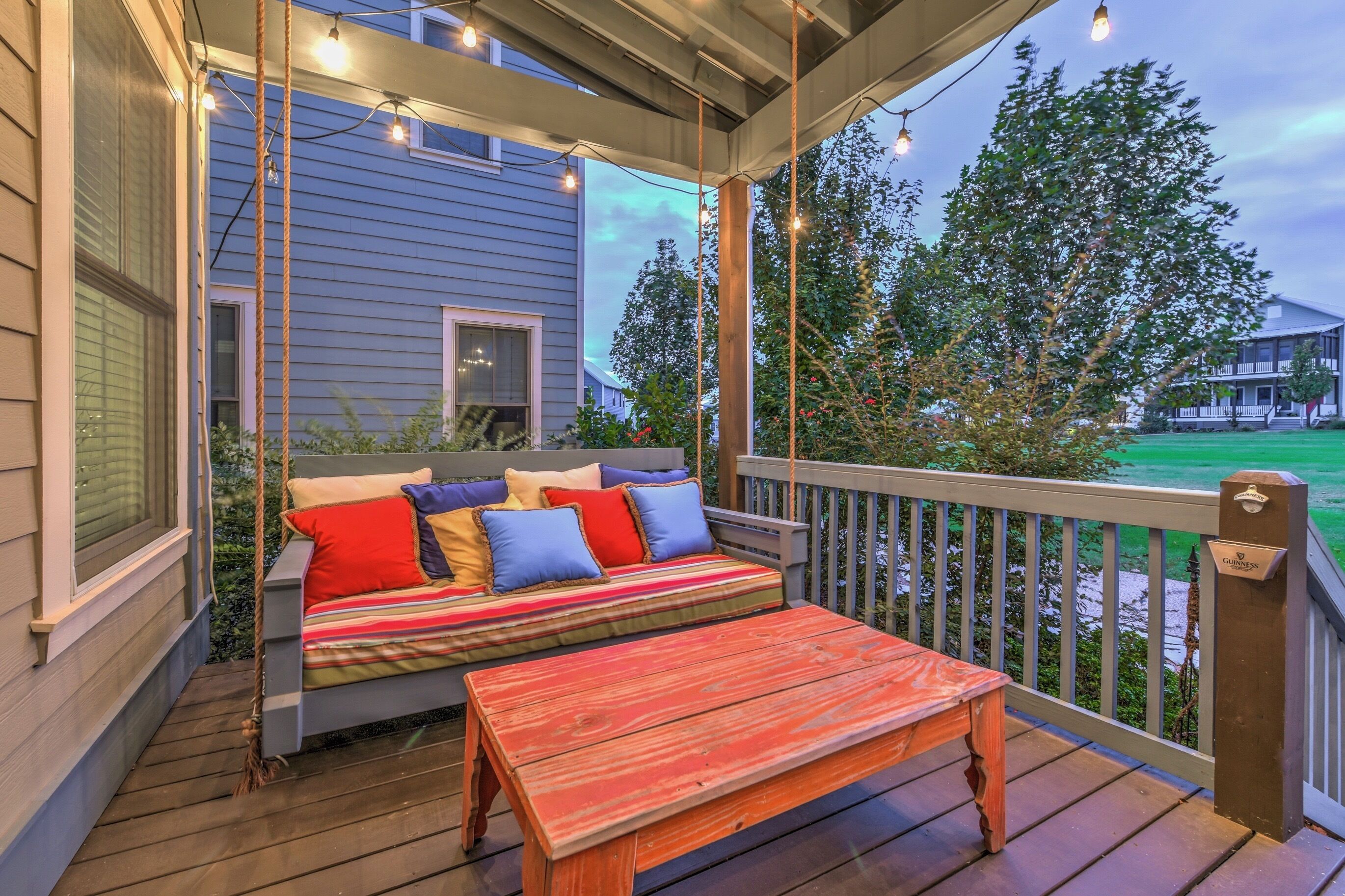 A wooden deck with a swing seat and a bench, overlooking a green landscape.