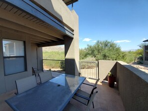 Enjoy a serene view of the surrounding landscape from this outdoor patio with a glass-top table and metal chairs.
