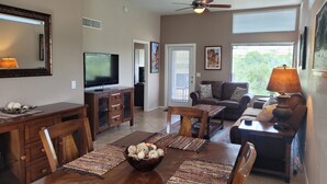 A spacious living room with a television, a ceiling fan, and a dining area with a wooden table and chairs. - Stunning - Inside and out! Beautiful Inside and Views of the Catalinas! (Tucson)