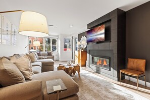 Bright living room with gas fireplace, wall-mounted TV, plush seating and large windows with natural light. - Main Street Ski-In/Out Condo | Rooftop Hot Tub|Managed by Park City Lodging (Park City)