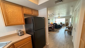A modern kitchen with wooden cabinets, a black refrigerator, and a built-in toaster.