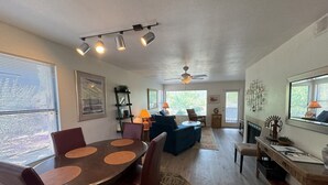 A spacious living area with a dining table, chairs, a sofa, a coffee table, and a fireplace.