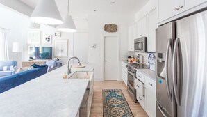 A modern kitchen with white cabinets, stainless steel appliances, and a central island. - Carlton Landing! Beautiful 3 Bedroom on Boardwalk (Carlton Landing)