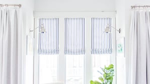 A modern living room with a white armchair, a blue sofa, and a striped window valance. - Carlton Landing! Beautiful 3 Bedroom on Boardwalk (Carlton Landing)
