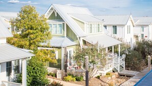 A row of white houses with green trim and metal roofs, surrounded by trees and a wooden deck. - Carlton Landing! Beautiful 3 Bedroom on Boardwalk (Carlton Landing)