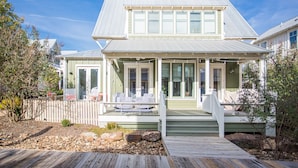 A two-story house with a covered porch, a deck, and a fenced yard. - Carlton Landing! Beautiful 3 Bedroom on Boardwalk (Carlton Landing)